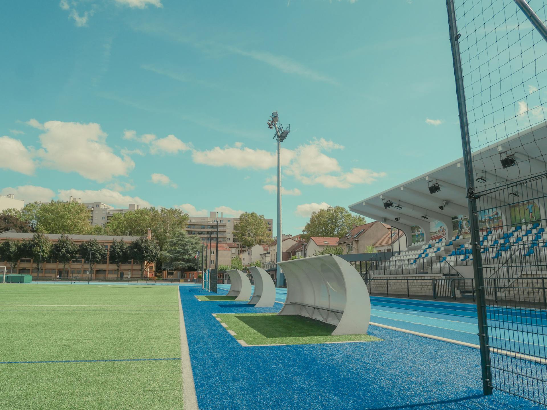 Wide-angle view of Vanves Tennis Stadium with empty seats under a clear sky.