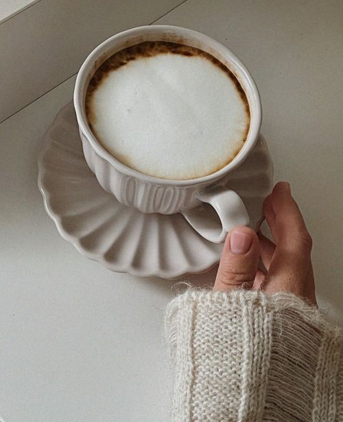 Free A hand holding a cappuccino cup, showing cozy comfort with a woolen sweater. Stock Photo