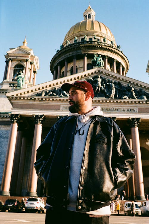Man in Leather Jacket Standing by Ornamented Building with Dome
