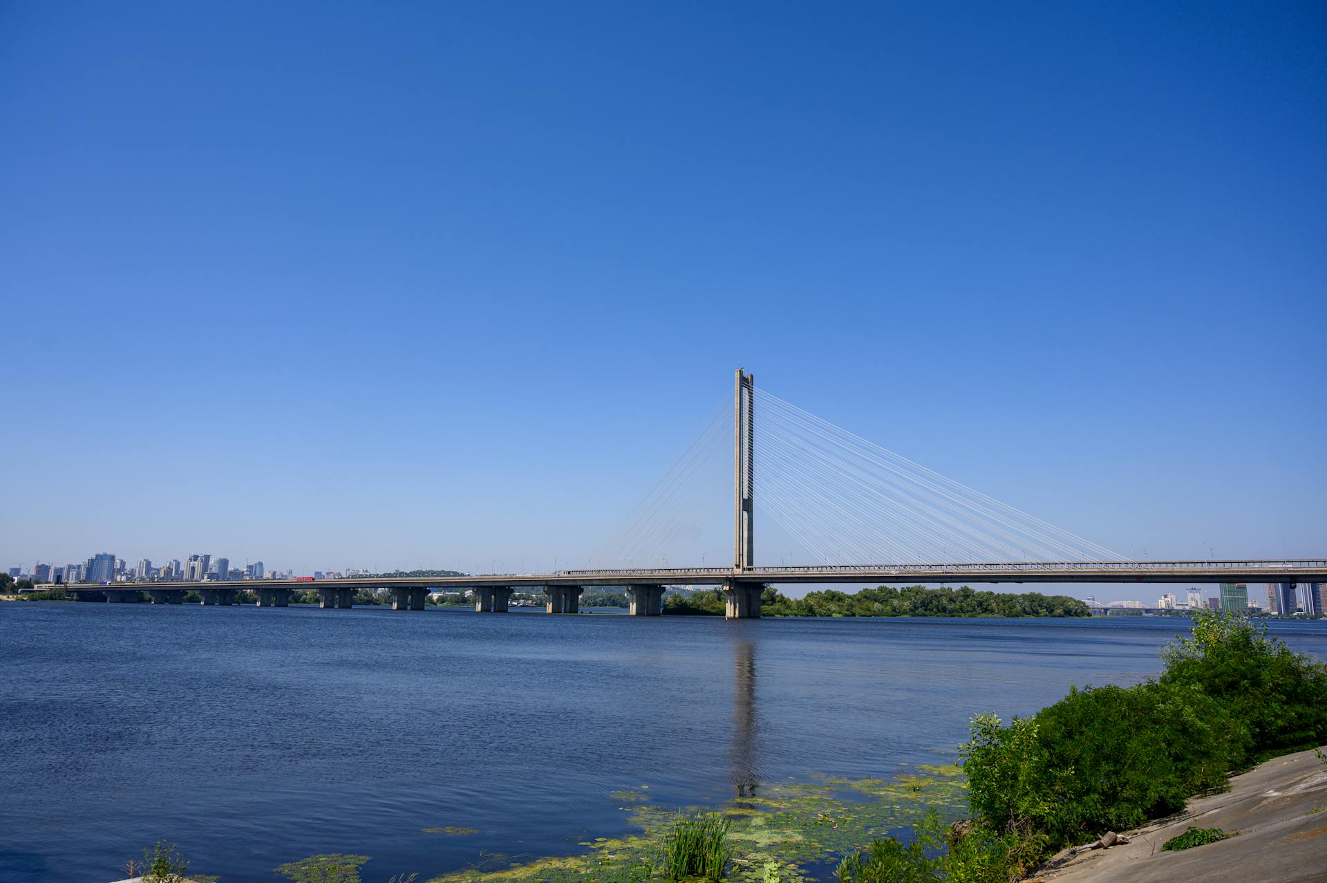 Scenic view of Pivdennyi Bridge spanning the Dnieper River in Kyiv, Ukraine under clear skies.