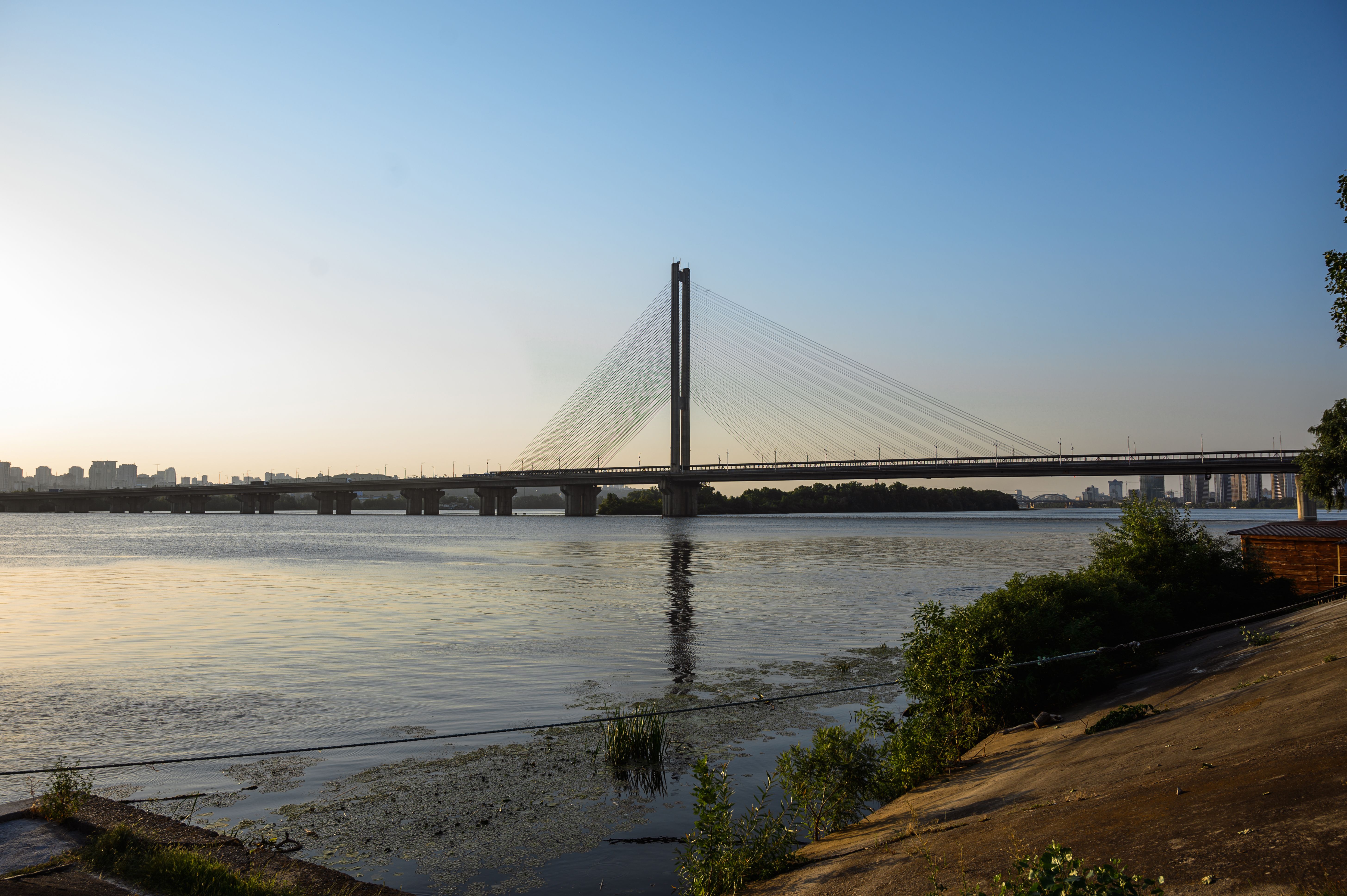 Schilderachtig uitzicht op een opgebouwde brug bij zonsondergang in Kyiv, Oekraïne, over een serene rivier.