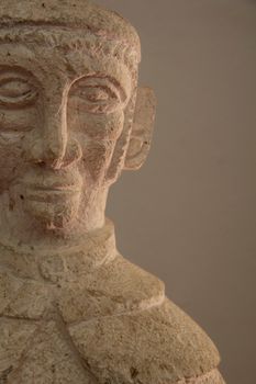 Close-up of an ancient stone sculpture against a neutral background.