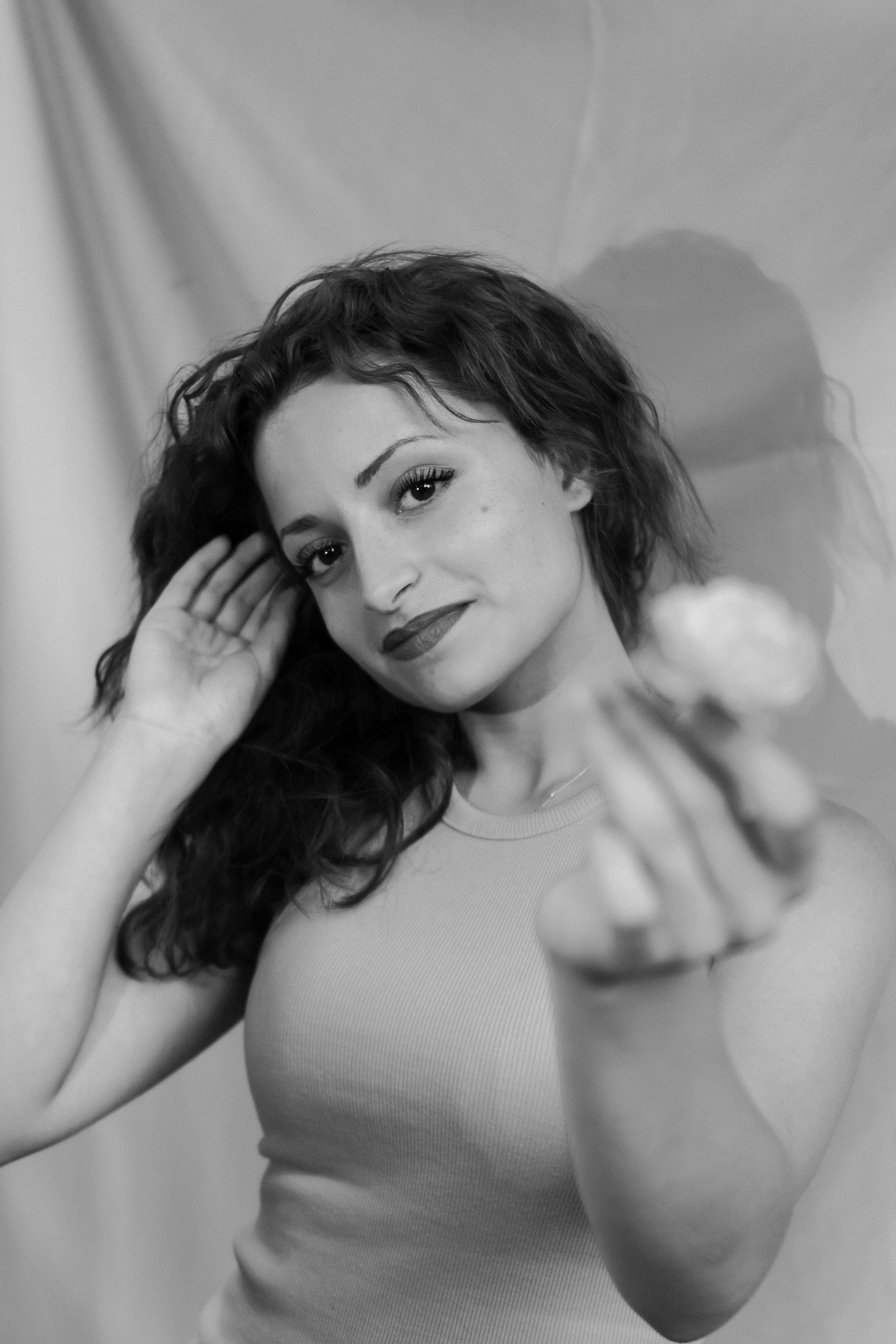 Charming black and white portrait of a woman with long hair offering a flower.