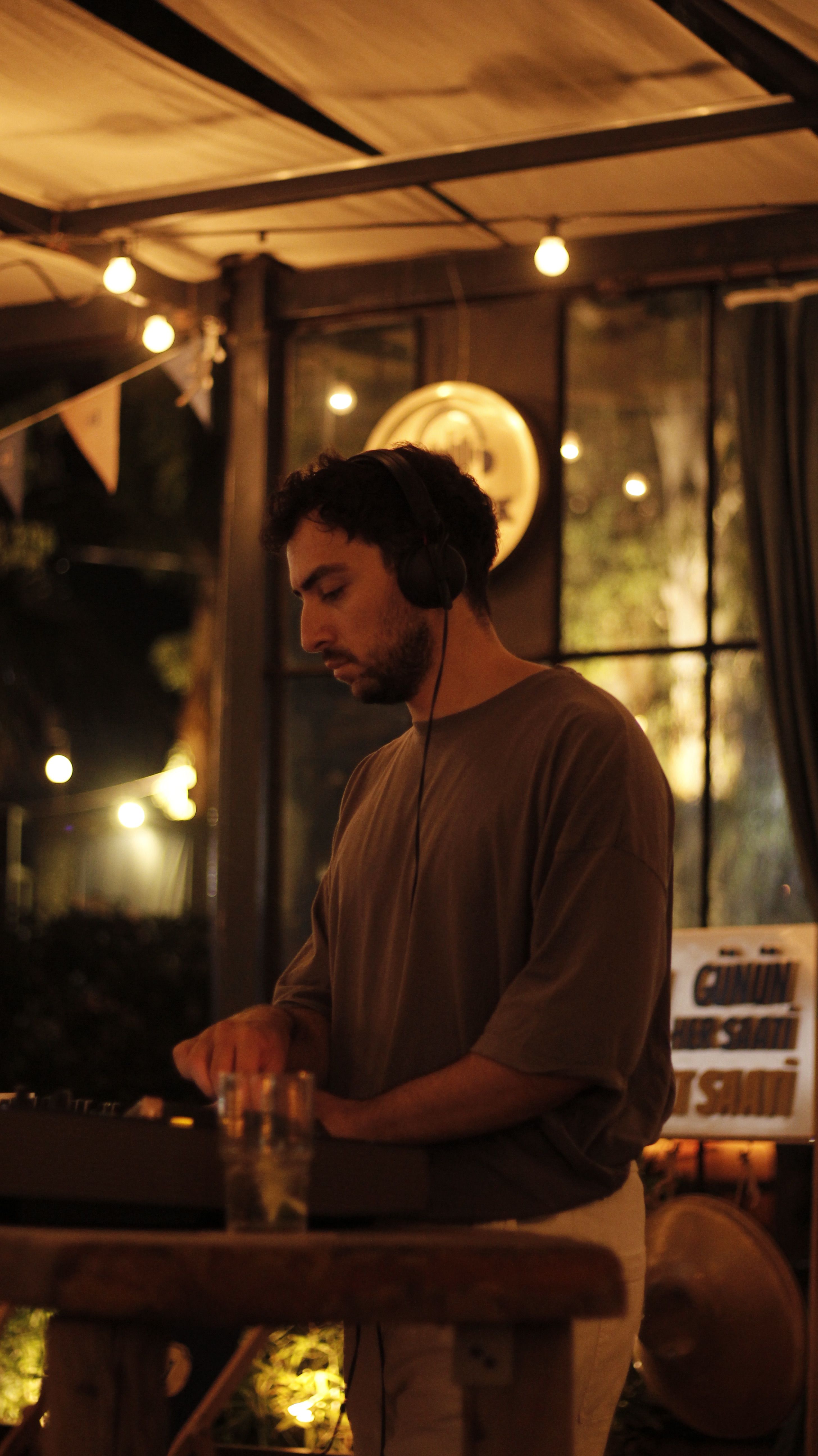 DJ with headphones mixing music at a night event outdoors.