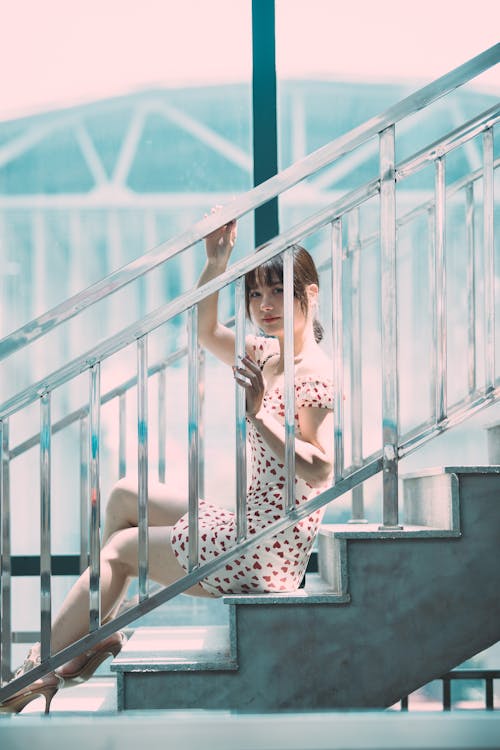 Young Woman in a Dress Sitting on the Stairs 