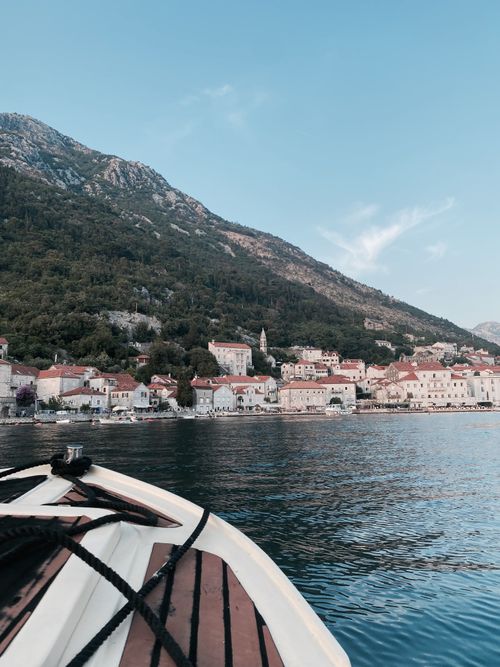 Free A boat sailing towards a picturesque coastal town in Montenegro, surrounded by mountains and clear blue sea. Stock Photo