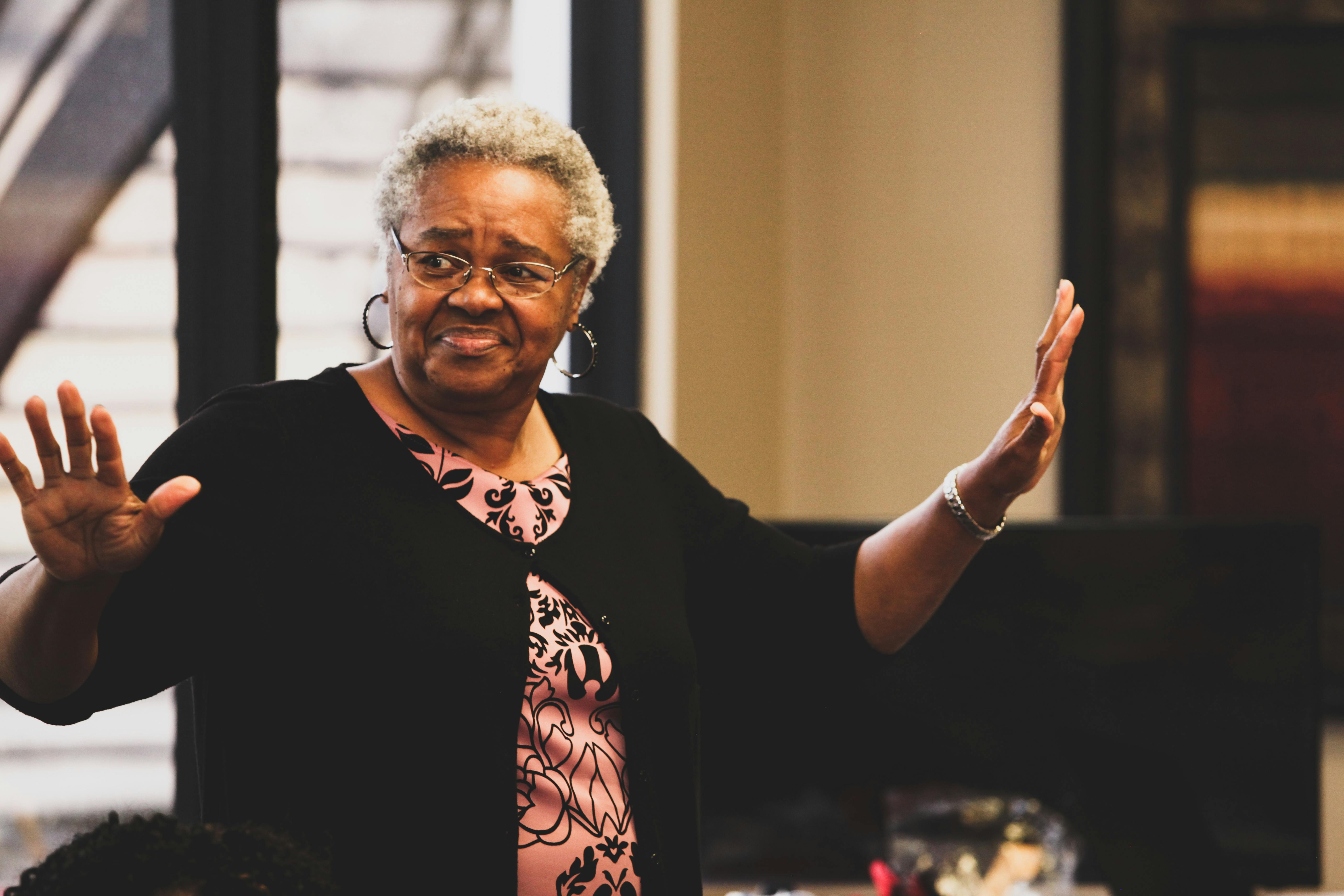 Senior adult woman gesturing while speaking indoors, showing confidence.