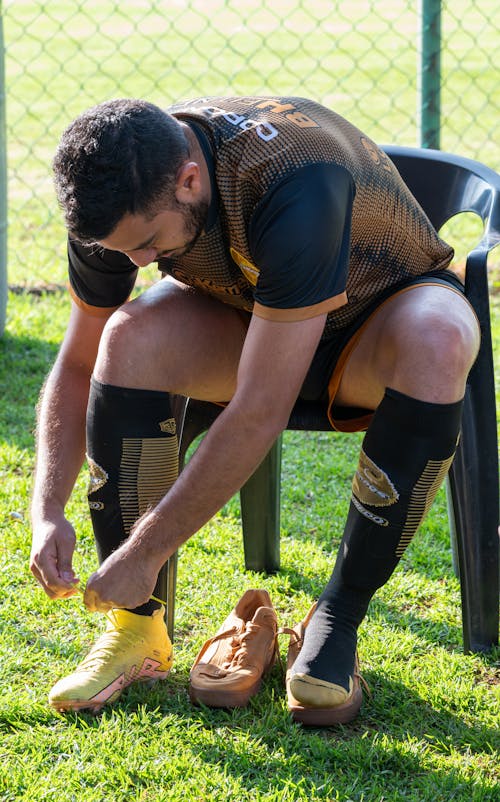 Free Football Player Sitting and Tying Shoes Stock Photo
