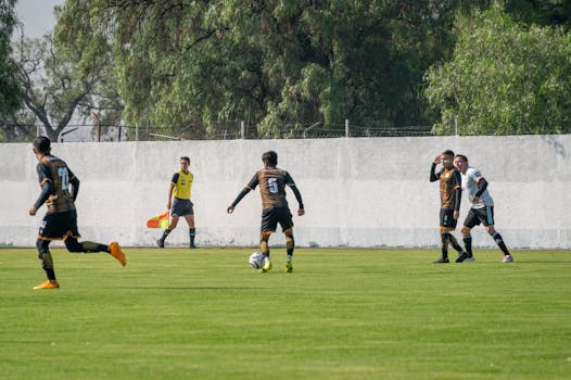 Football players actively engage in a match on a sunny day outdoors, showcasing teamwork and athleticism.