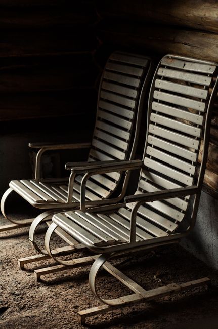 A pair of vintage wooden lounge chairs in a rustic interior setting, showcasing natural wood and metal design.