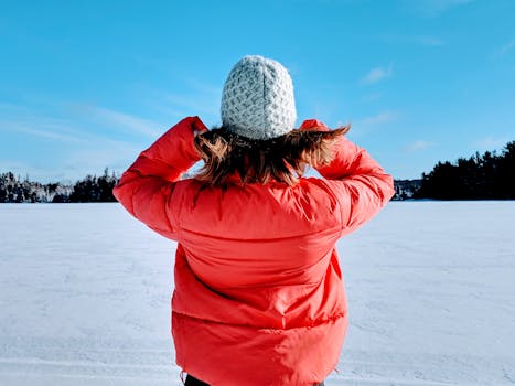 A person in a red jacket and beanie enjoys a crisp winter day in Whitestone, Canada.