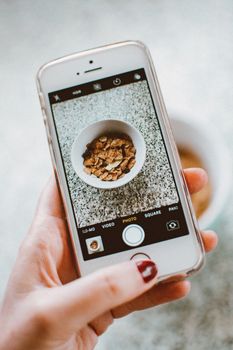 A smartphone capturing an image of a bowl of cereal, perfect for food and technology themes.