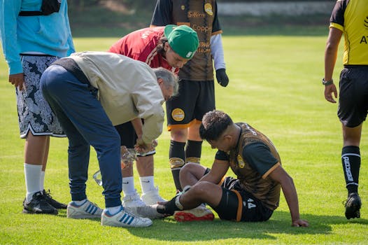 An injured soccer player receiving on-field medical attention during a game.