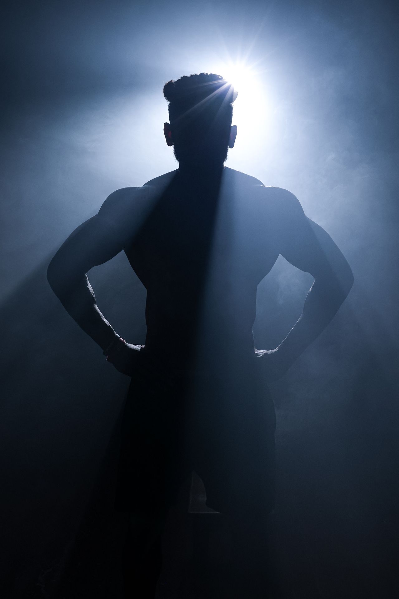 A powerful silhouette of a muscular man against a dramatic smoky backdrop