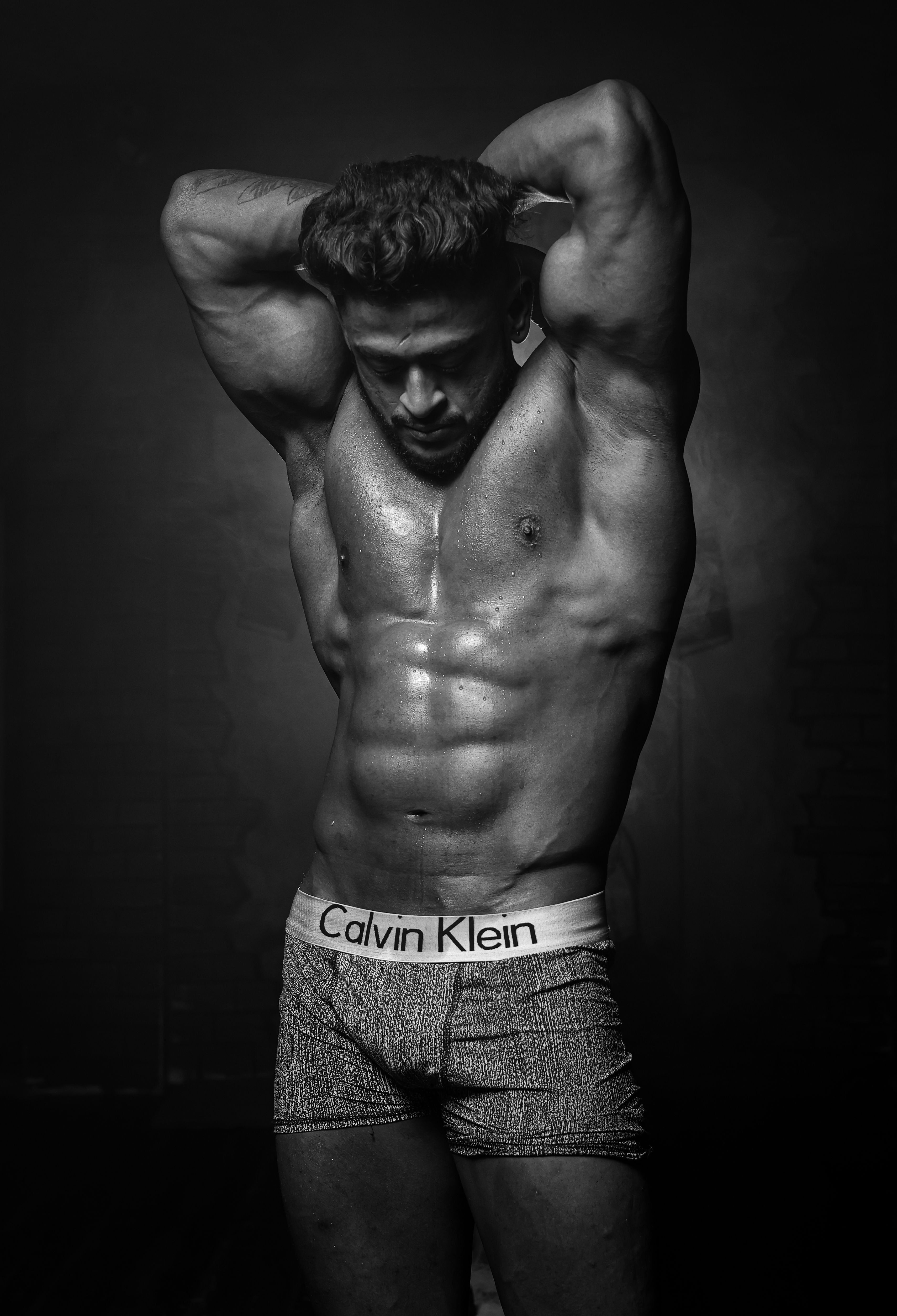 Dynamic black and white photo of a muscular man showcasing strength and physique.