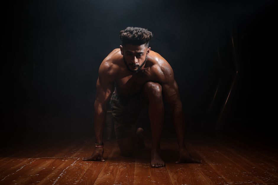 Dynamic image of a muscular man in a kneeling start position, highlighting strength and focus.