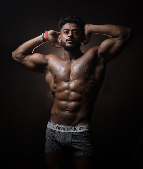 Free Muscular man posing shirtless in a studio, showcasing fitness and physique. Stock Photo