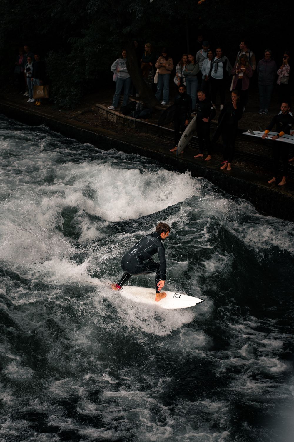 Surfer călărind valul staționar de pe pârâul Eisbach din München