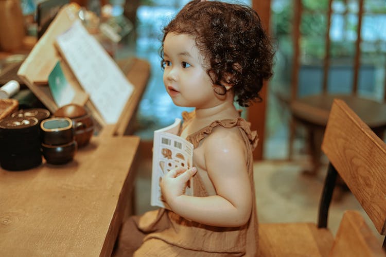 Little Girl With A Book Sitting At The Counter