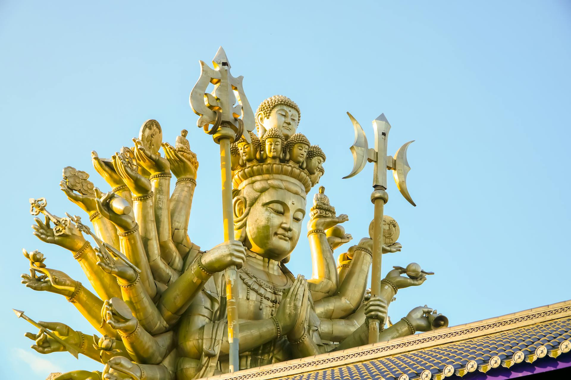 The majestic Guishan Guanyin statue bathed in golden light against a clear sky, showcasing spiritual artistry.