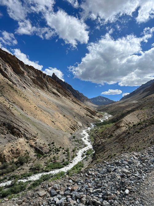 Free A breathtaking view of a rugged mountain canyon with a winding valley stream under a blue sky. Stock Photo