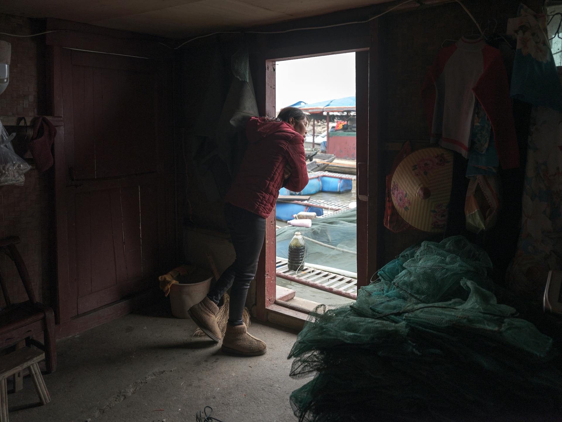 Woman Peeking through Doorway in House in Village