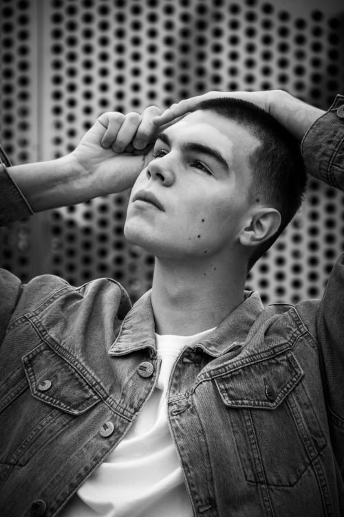 Free Black and white portrait of a stylish young man in a denim jacket looking upward. Stock Photo