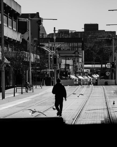 Person Walking on Tram Tracks in City