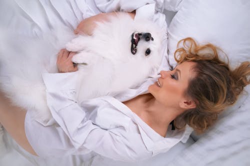 Brunette Woman Lying in Bed with Pomeranian Dog