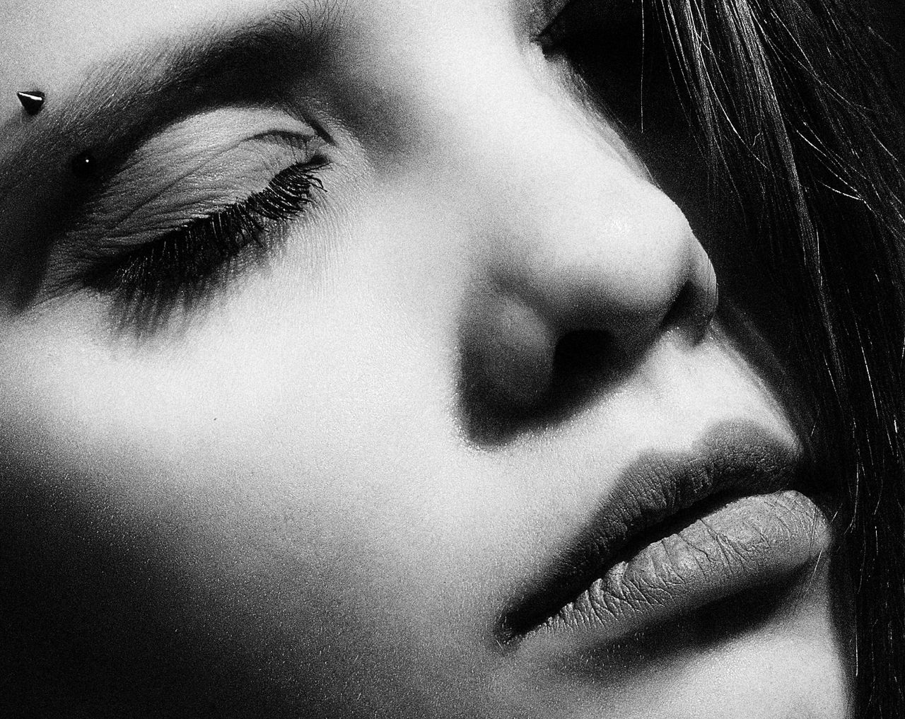 artistic close up black and white portrait of a woman with an eye pier