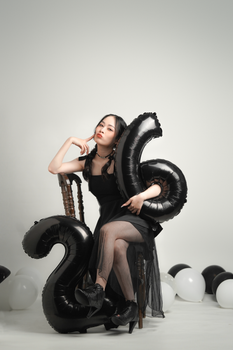 Elegant woman celebrating her 26th birthday with black balloons in a studio setting.