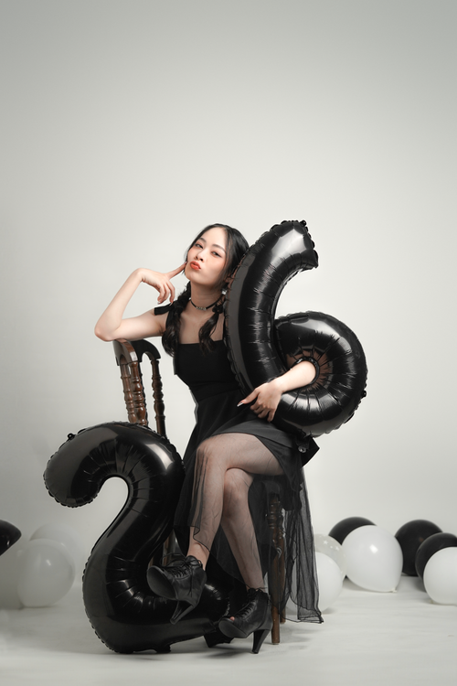 Free Elegant woman celebrating her 26th birthday with black balloons in a studio setting. Stock Photo