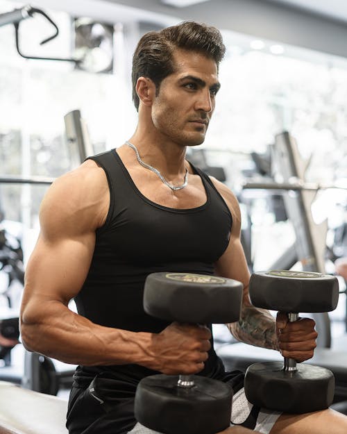 Man in a Tank Top Exercising with Dumbbells