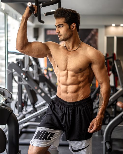 Free Muscular man standing shirtless in a gym, engaging in a workout with state-of-the-art equipment. Stock Photo