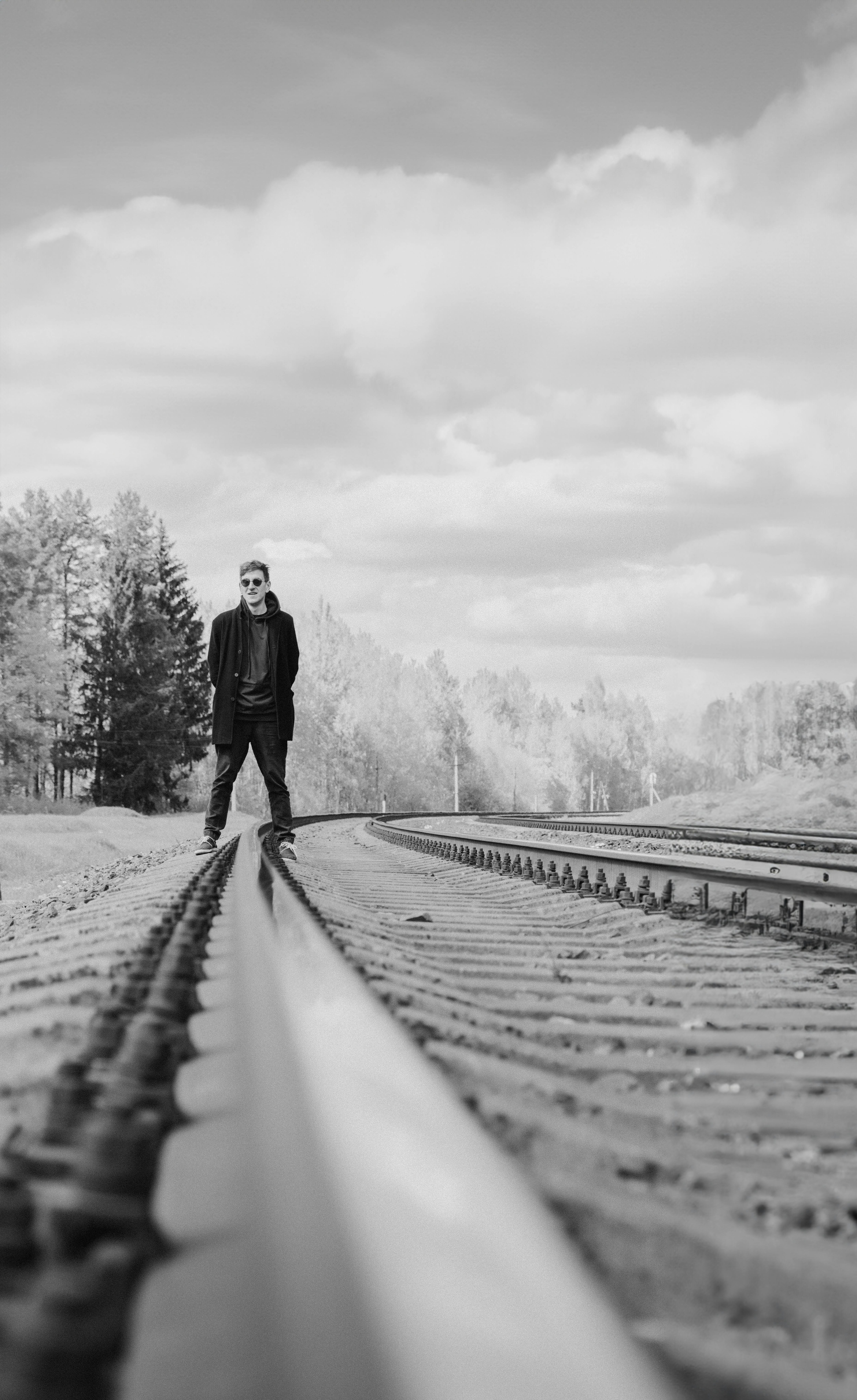 Black and white photo of a man in sunglasses standing on railway tracks in Vitebsk.