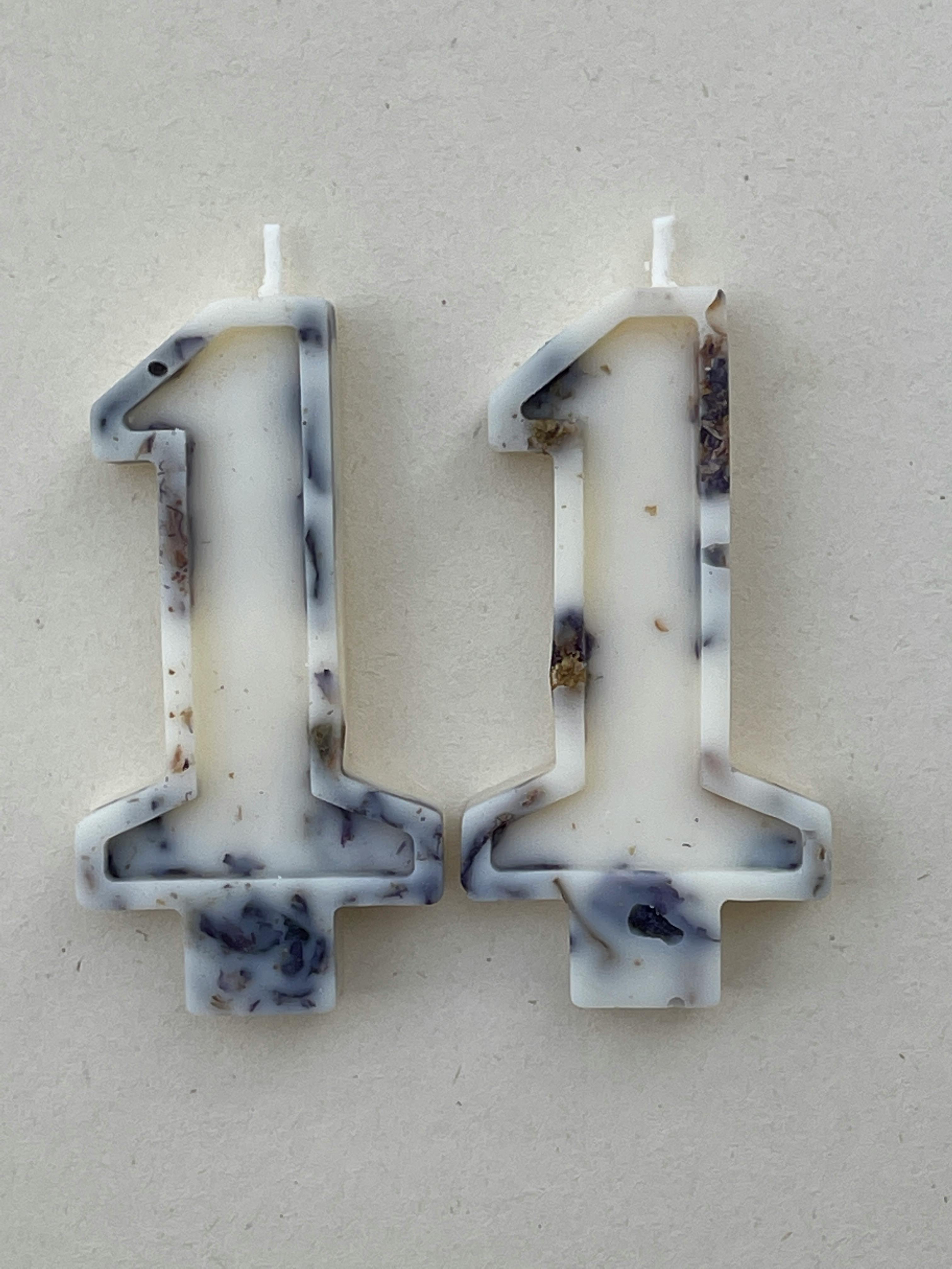Rustic number eleven birthday candles with marbled design on a beige surface.