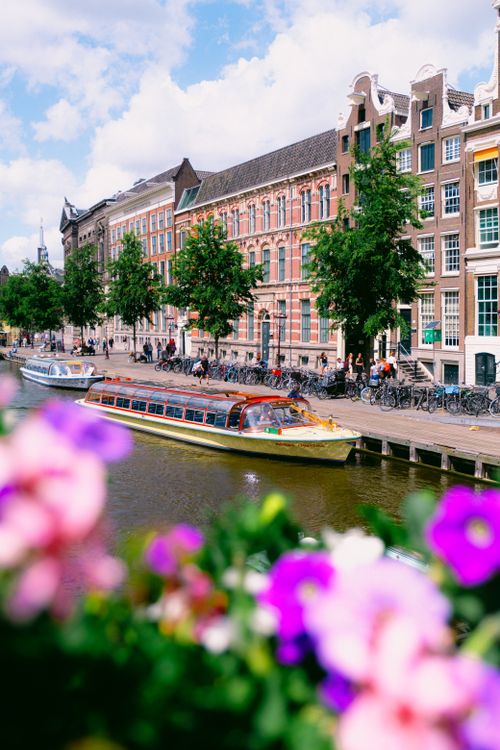 Free Charming Amsterdam canal scene with colorful boats and classic architecture. Stock Photo