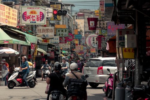 Free Lively city street filled with scooters, cars, and vibrant signage in an Asian city. Stock Photo