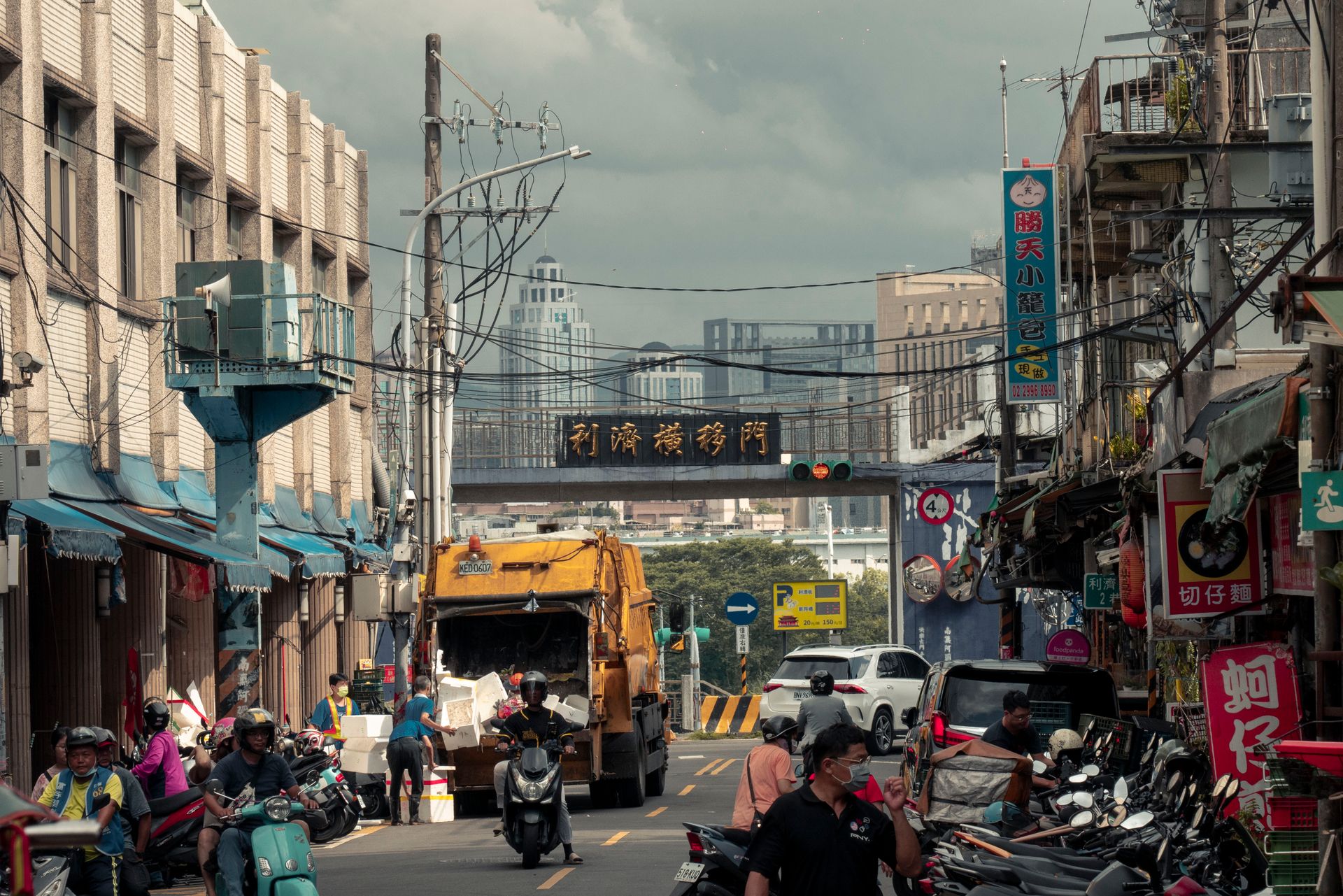 Vibrant urban street filled with vehicles and people amidst high-rise buildings.