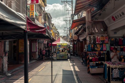 Busy Asian street market with vibrant stalls under a sunny sky. Perfect for urban and travel themes.