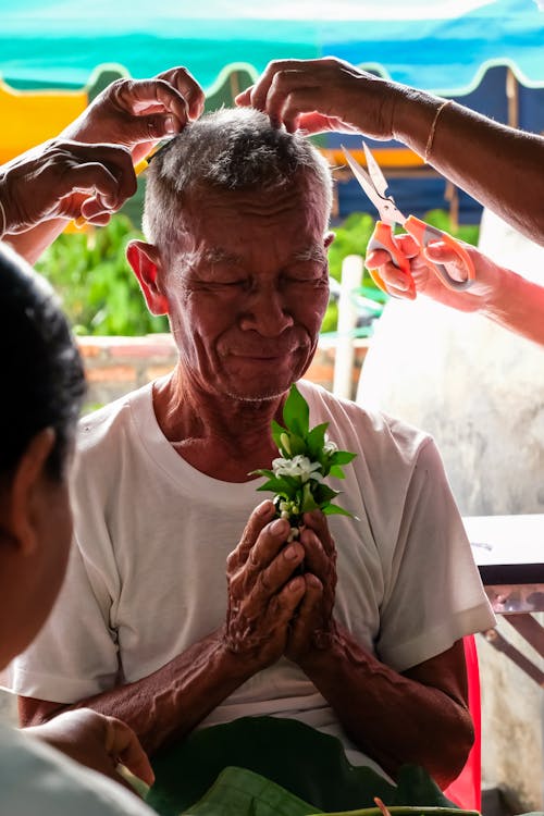 Man Holding Flowers While Getting a Haircut