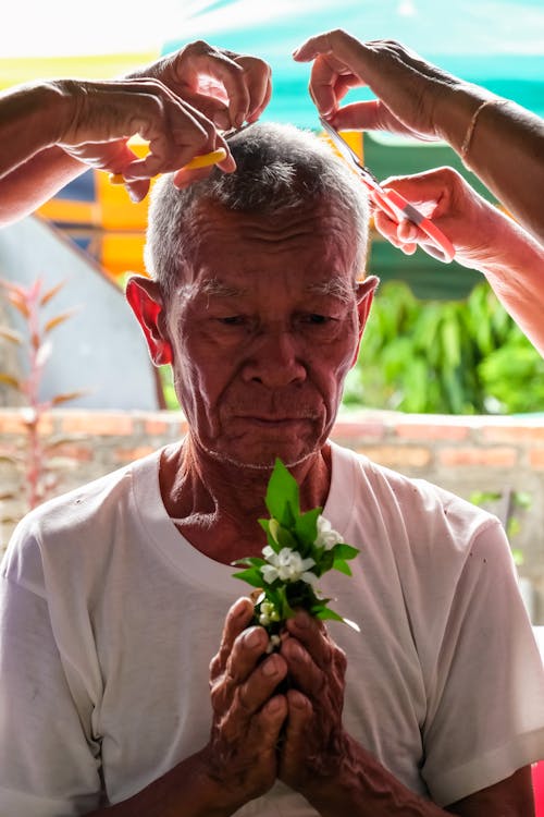 Hands Cutting Hair of Praying Man