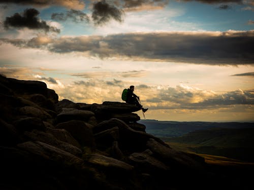 Man Sitting on Cliffs in a Mountain Valley 