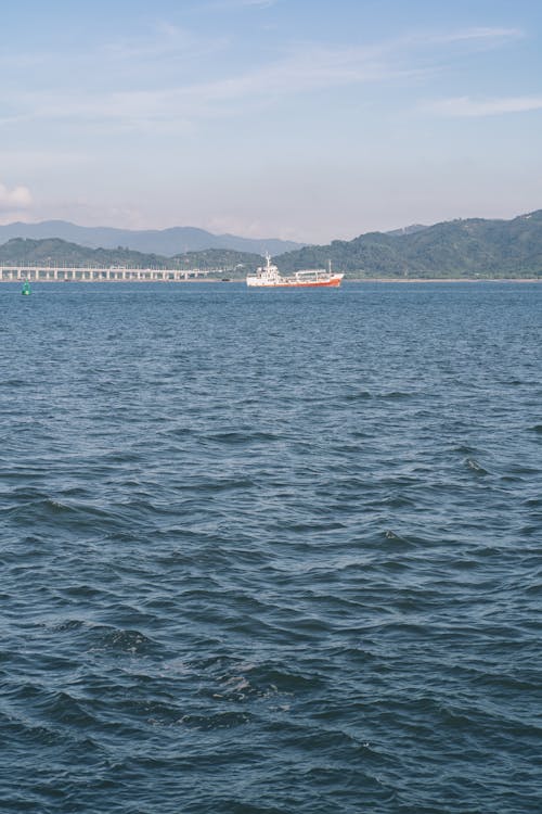 Commercial Ship Sailing against Mountain Shore