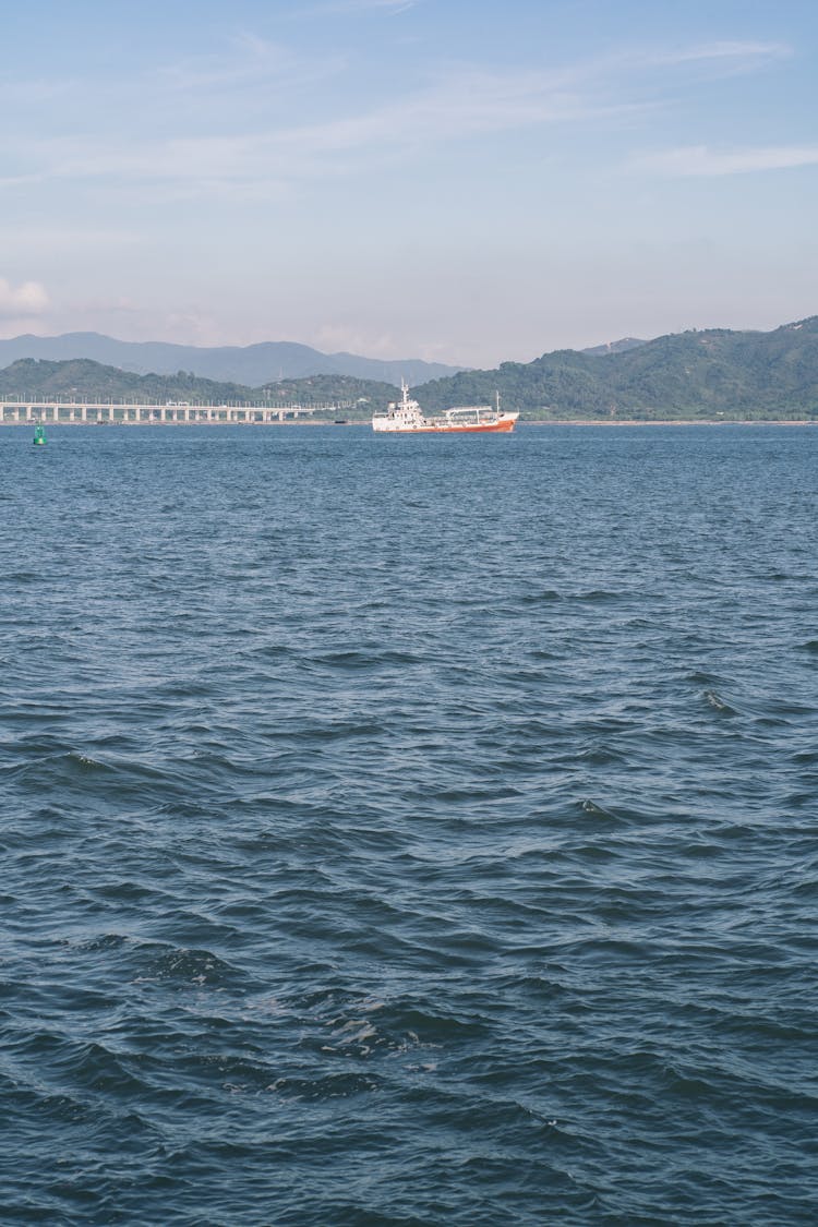 Commercial Ship Sailing Against Mountain Shore