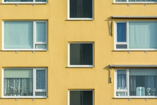 Close-up view of a yellow apartment building facade with windows and balconies.