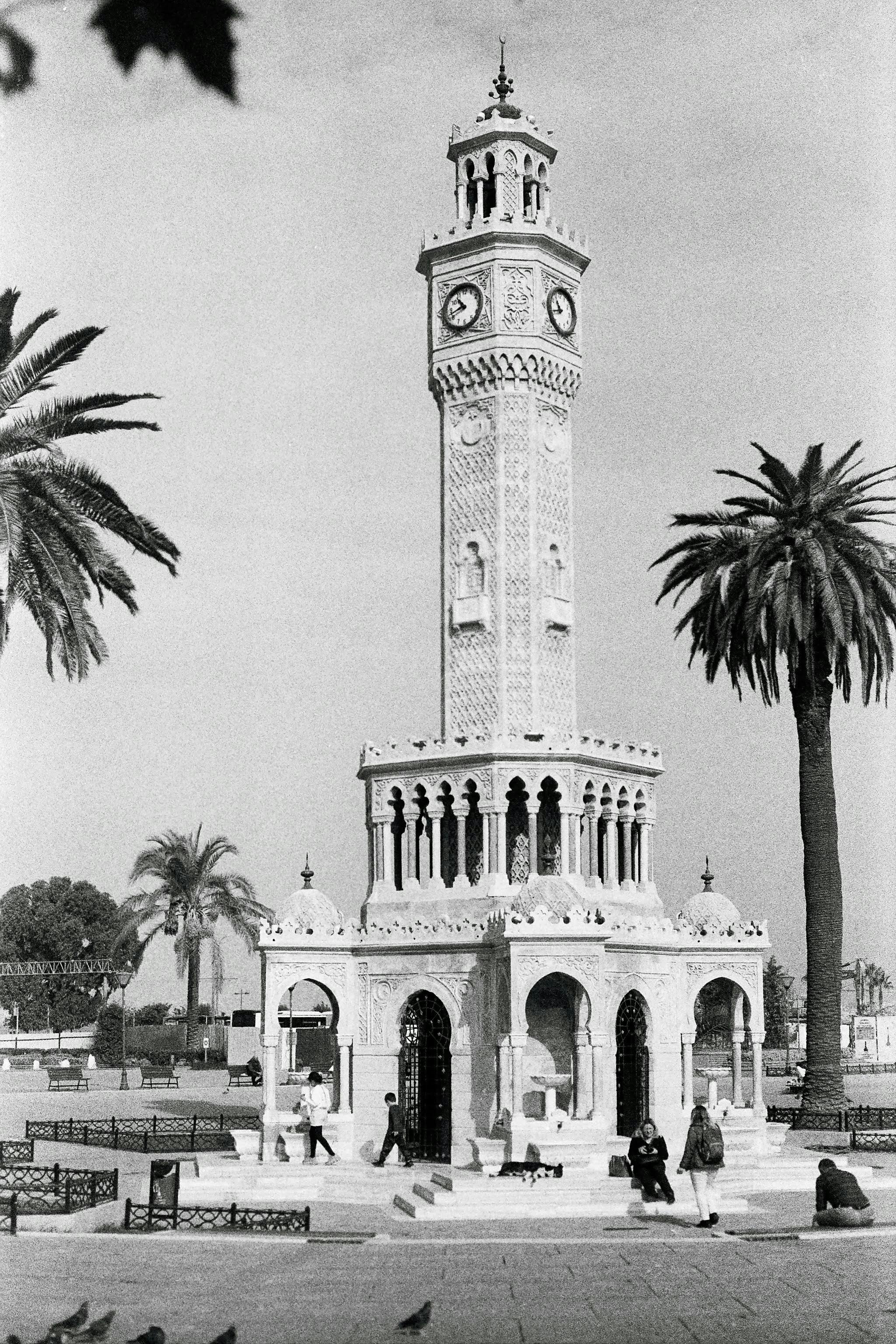 Black and white photo of Izmir Clock Tower, a significant landmark in Turkey, surrounded by palm trees.