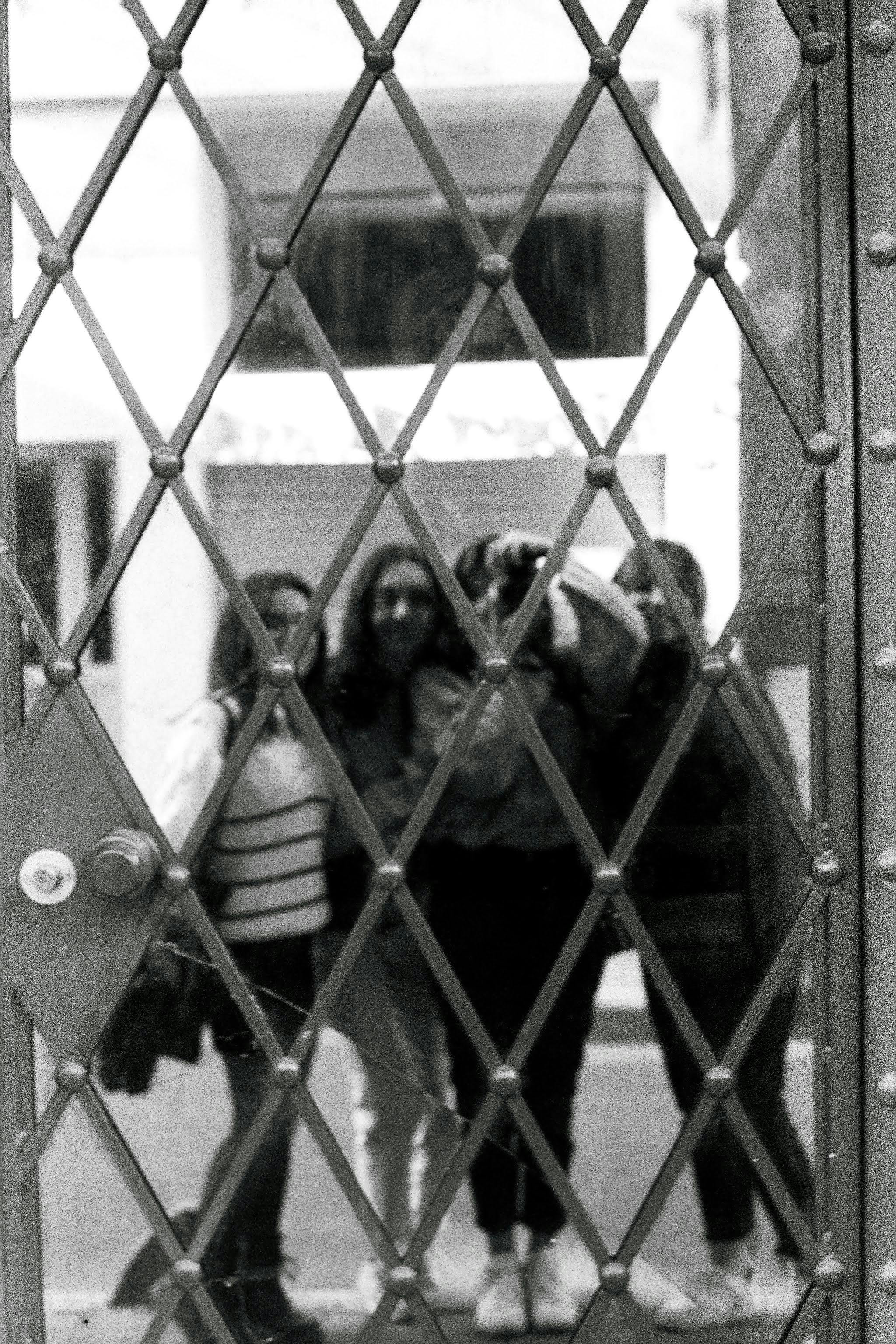 Women Taking Pictures behind Door Bars · Free Stock Photo