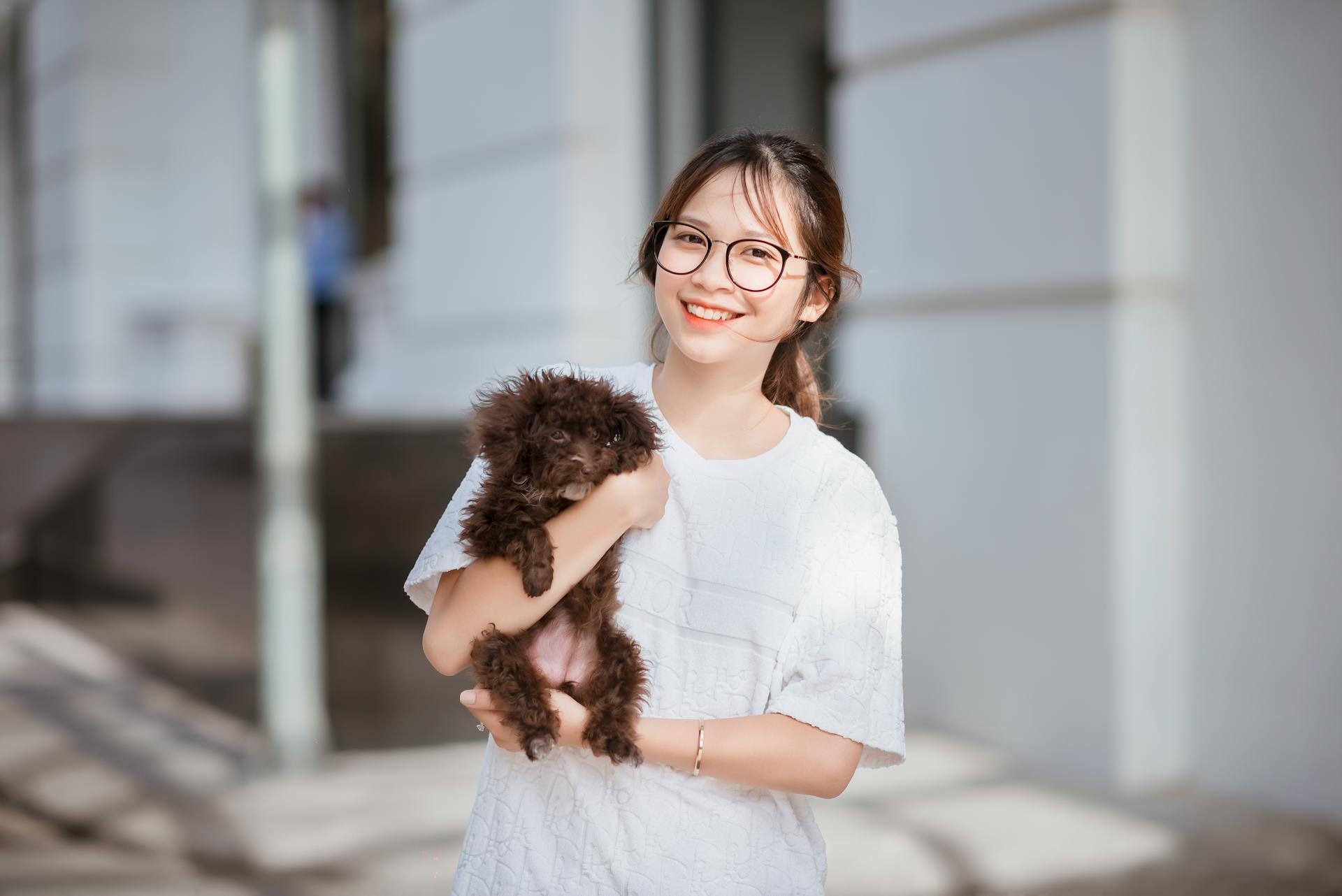 A Girl Holding a Puppy and Smiling