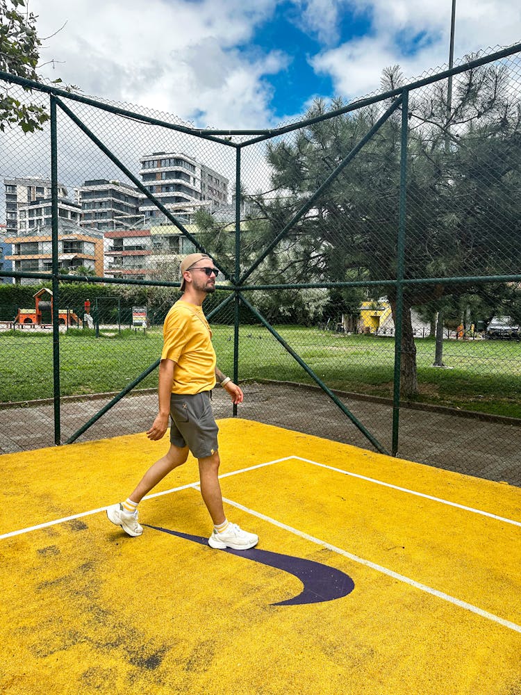 Man In Yellow T-shirt Walking On Yellow Tennis Court